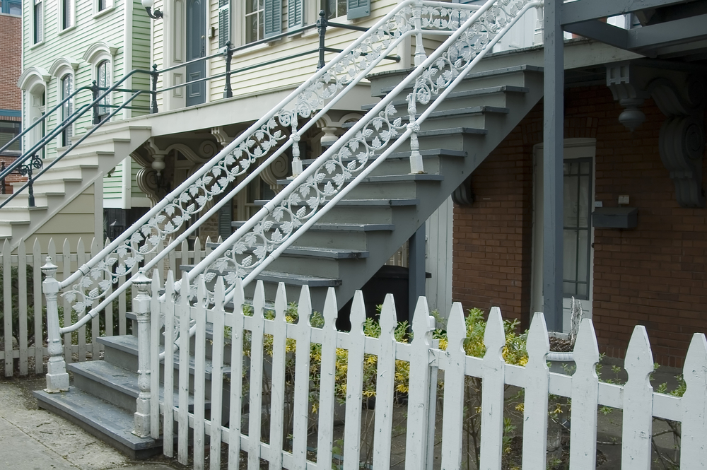 Fancy white ironwork on wooden stairway in urban neighborhood