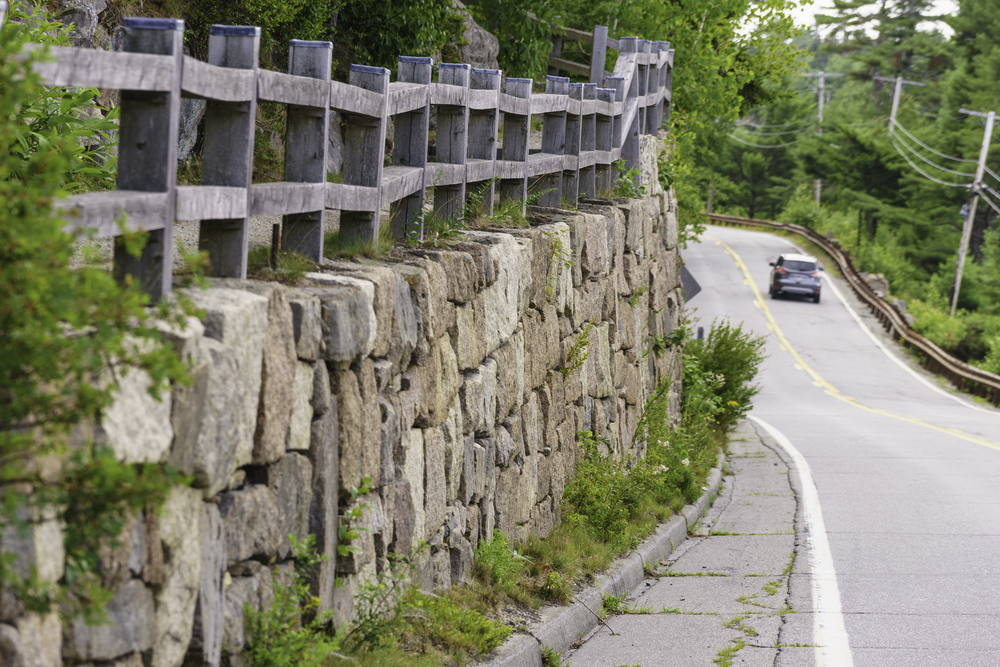Long stone wall topped by wooden fence along a winding road on Mount Desert Island, Maine, USA, in summer